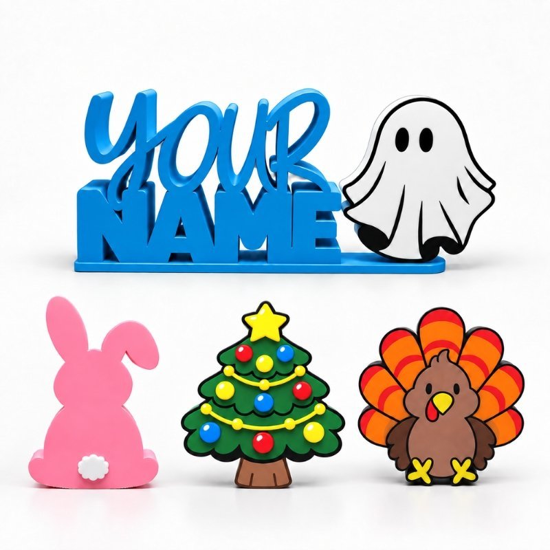 Blue personalized Namelet desk sign with ghost, Christmas tree, pink bunny, and turkey interchangeable Sidekicks displayed in front.