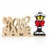 Holiday Lamp Post SideKick Cream-colored stacked Namelet displaying “YOUR NAME” with a festive Holiday Lamp Post SideKick featuring yellow windows, snow accents, and a red bow on a white background.